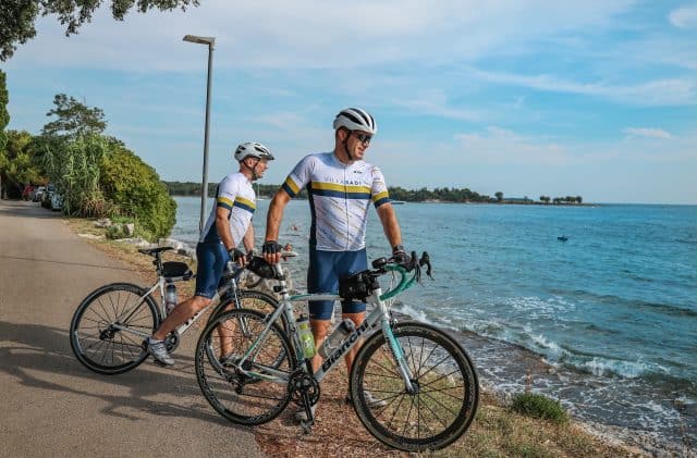 Biciklisti uživaju u slikovitoj vožnji uz obalu po sunčanom danu.