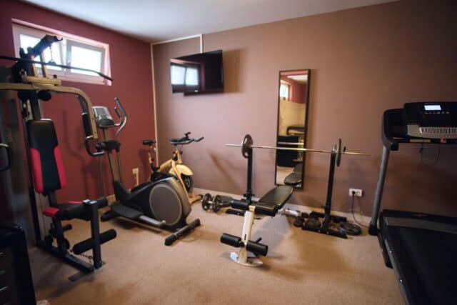 Kućna teretana s fitness opremom i utezima.