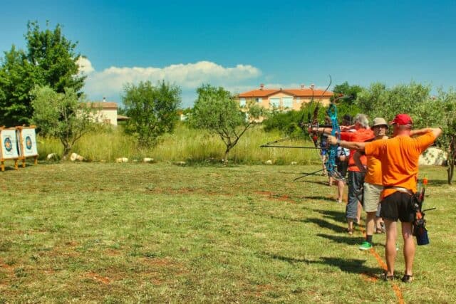 Grupa ljudi trenira streličarstvo na otvorenom