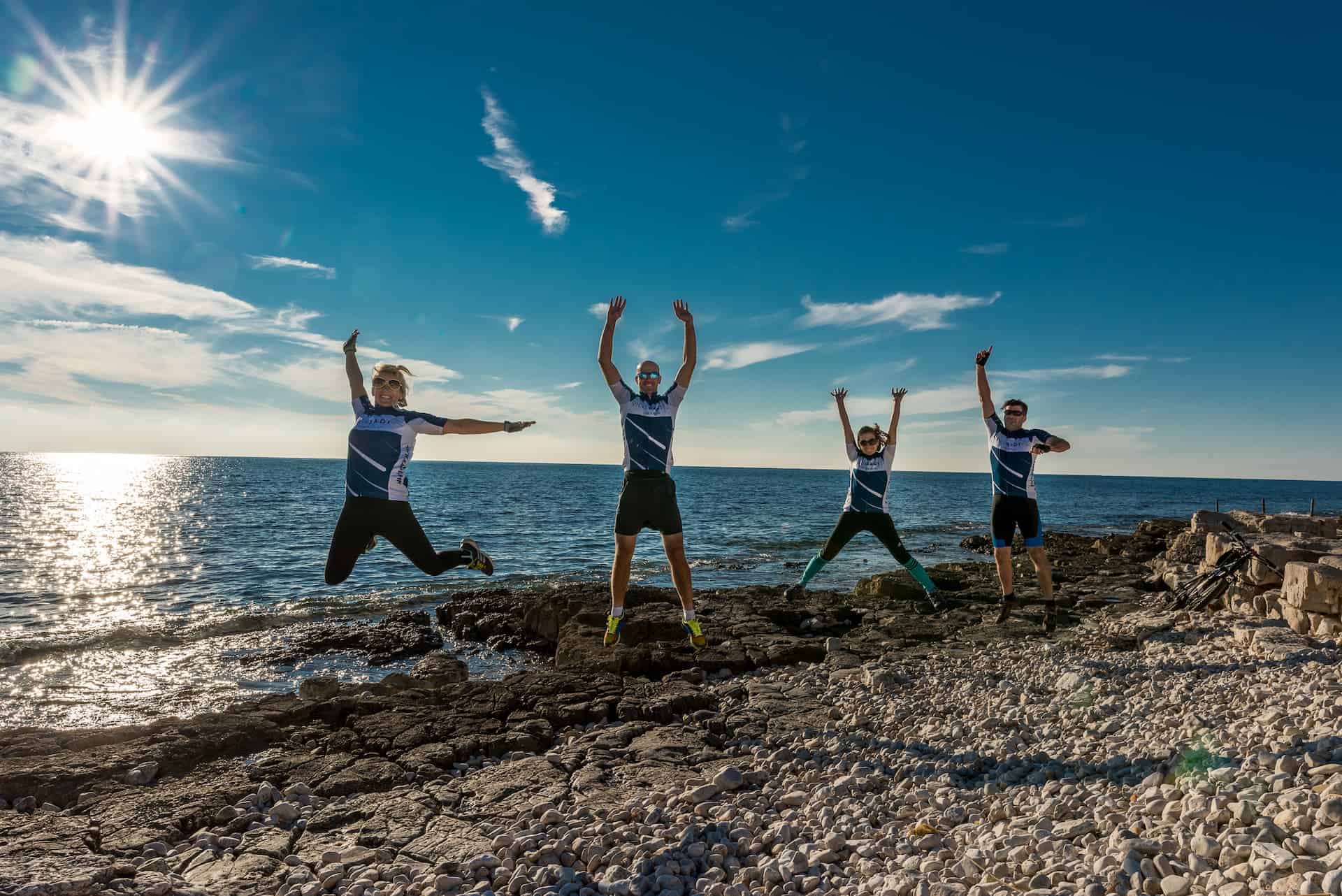 Ljudi skaču na plaži uz more.