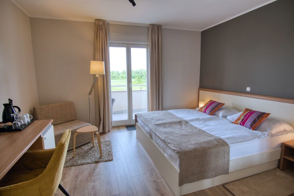 Moderna hotelska soba s bračnim krevetom i balkonom.