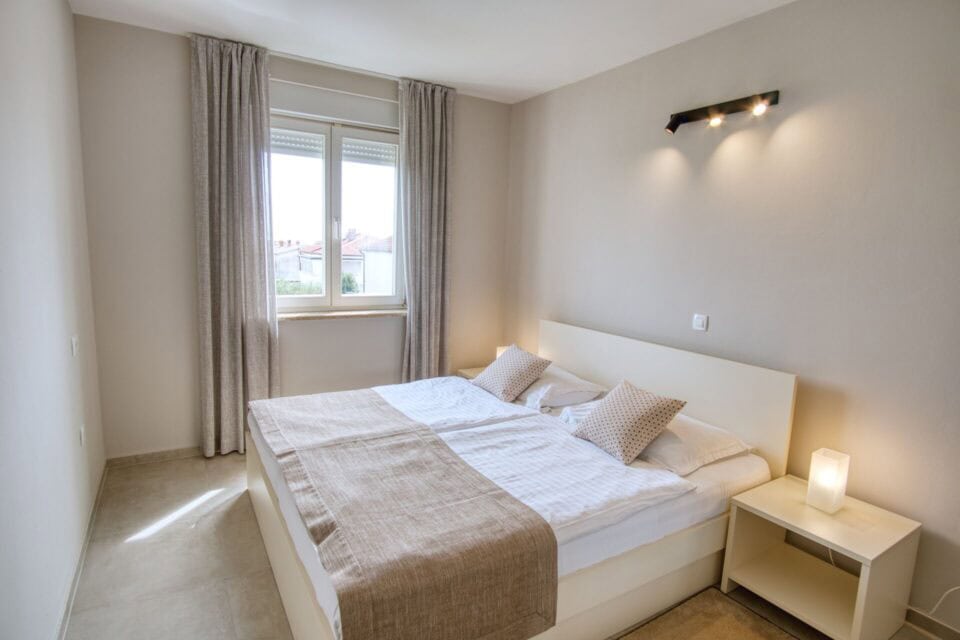 Moderna spavaća soba s velikim krevetom i prozorom.