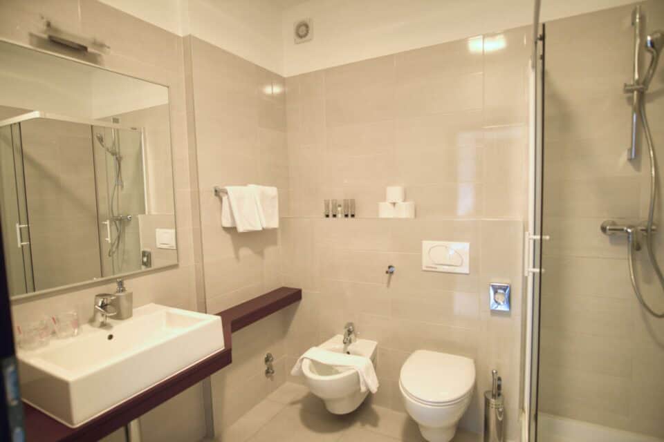 Moderna kupaonica s tušem i bijelim pločicama.