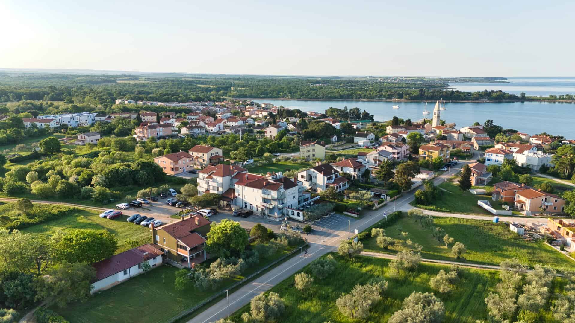 Panorama priobalnog sela uz more i zelenilo.