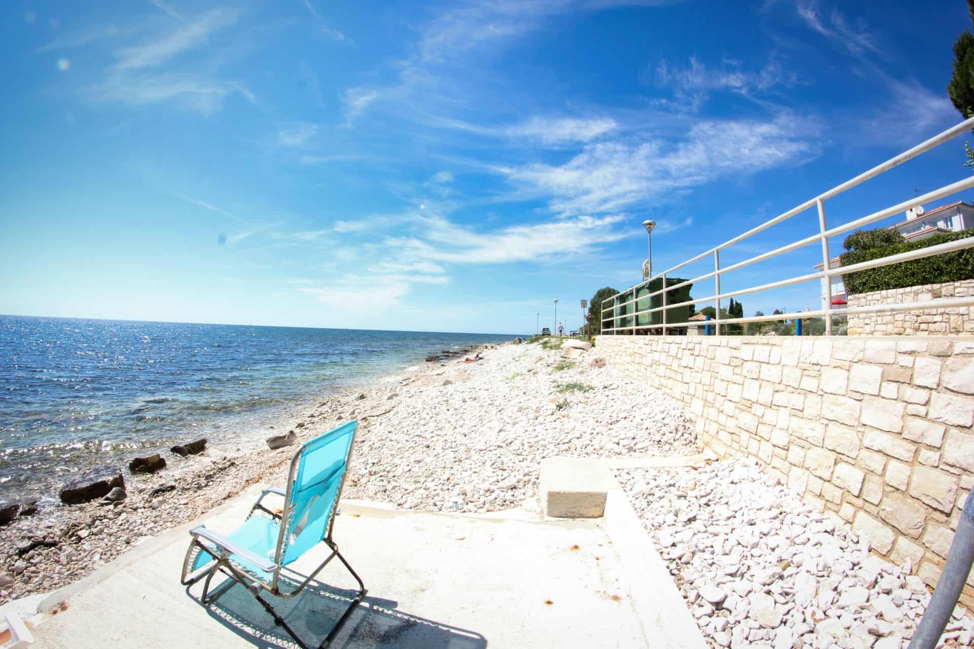 Plaža s plavom ležaljkom uz more.